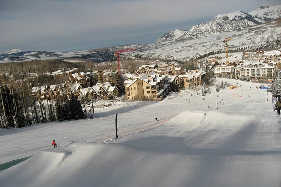 a snow covered ski run looking down at the town of telluride
