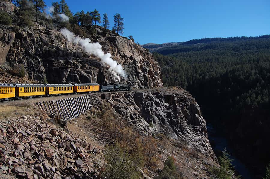 a train traveling around the bend of a steep cliff