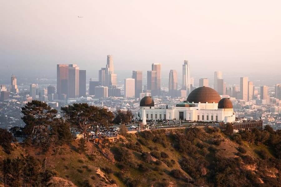 the griffith observatory on top of a hill with downtown LA in the background