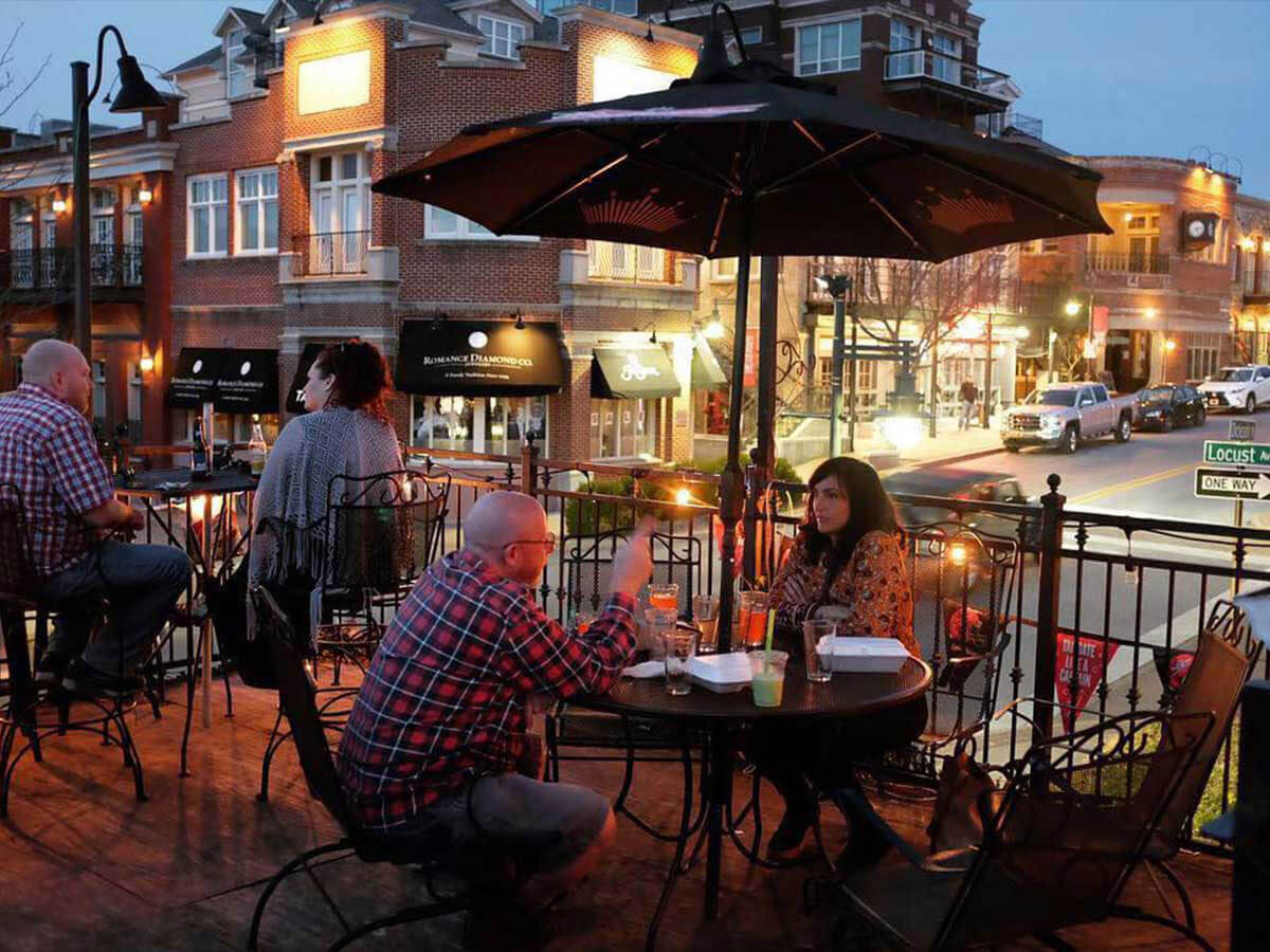 patrons eat dinner on the patio of a restaurant overlooking dickson street