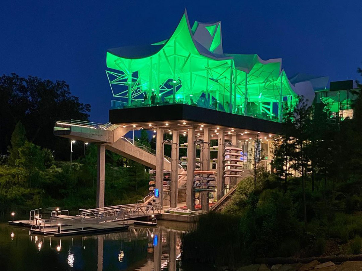 the boathouse at gathering place tulsa illuminated in green at night
