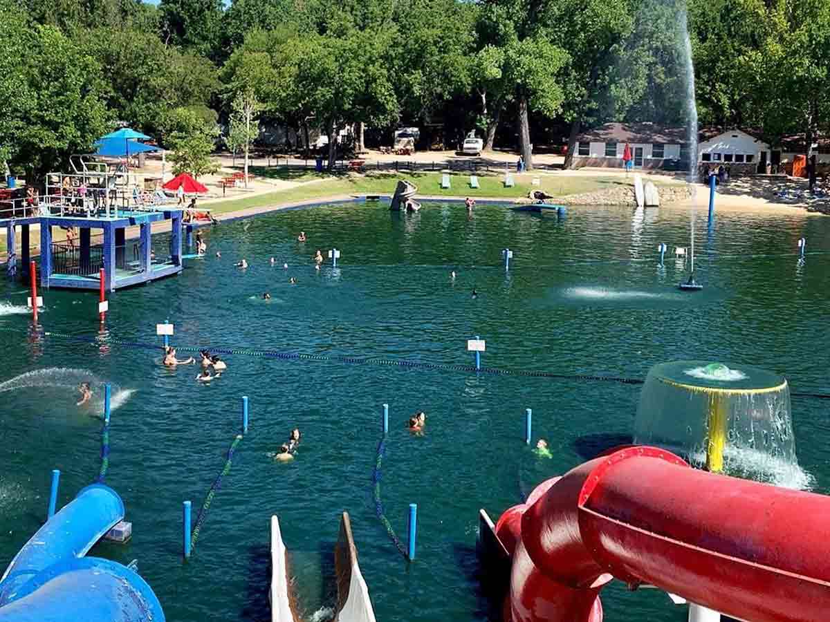 a portion of burger's lake with water slides and fountains and people swimming