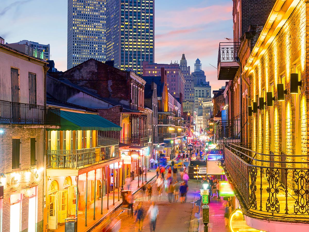 a view down bourbon street in the evening with building lights glowing