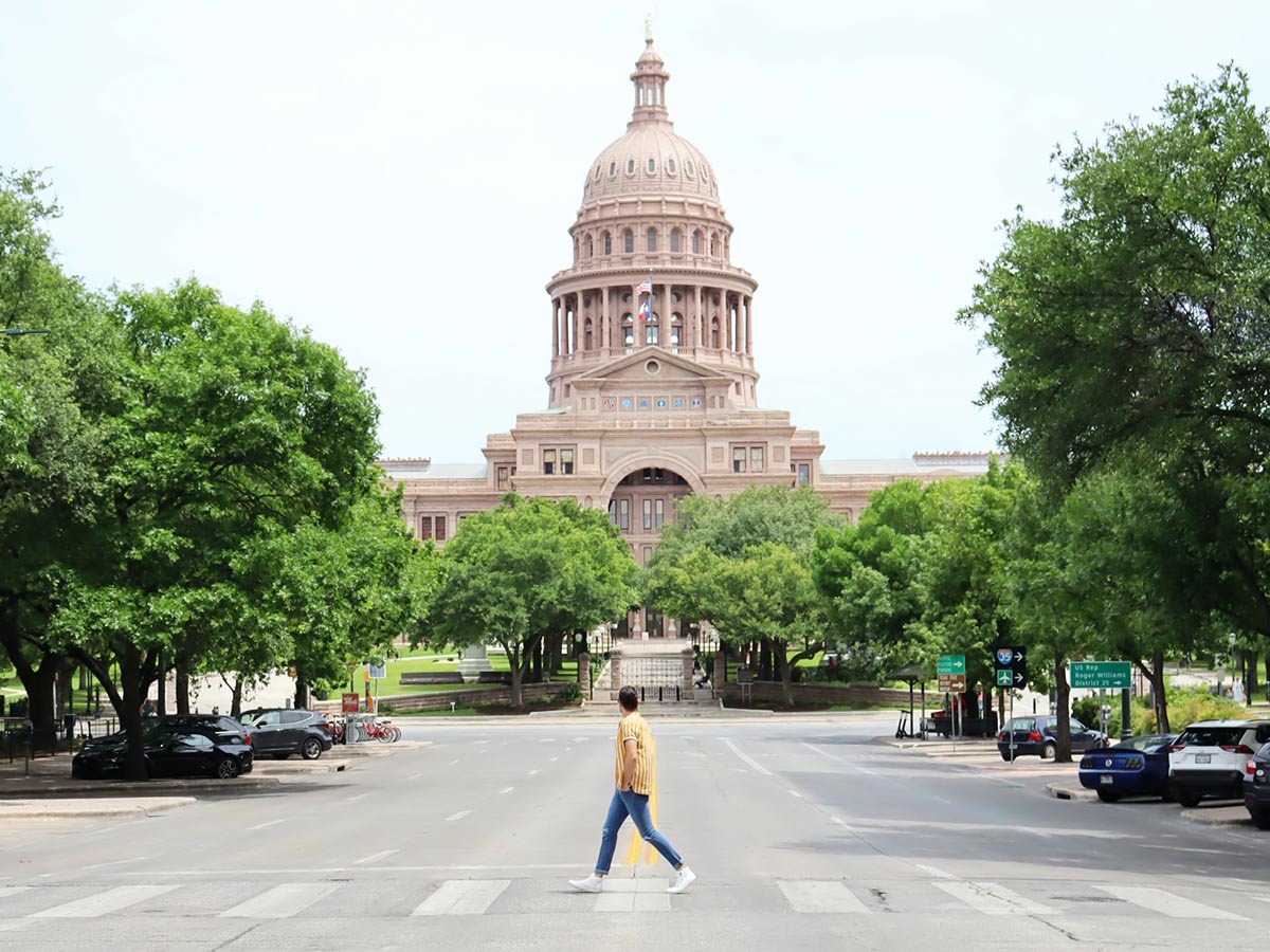 a man walking across the street in front of the texas state capitol