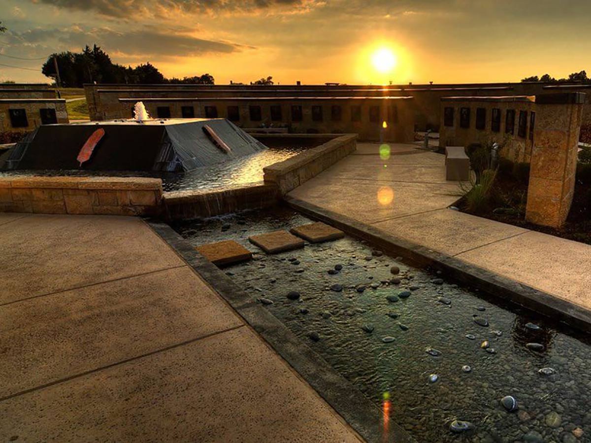 sun setting behind a fountain at the chickasaw cultural center