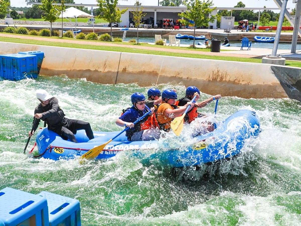 a group of people try to steer an inflatable boat through rapids at riversport okc