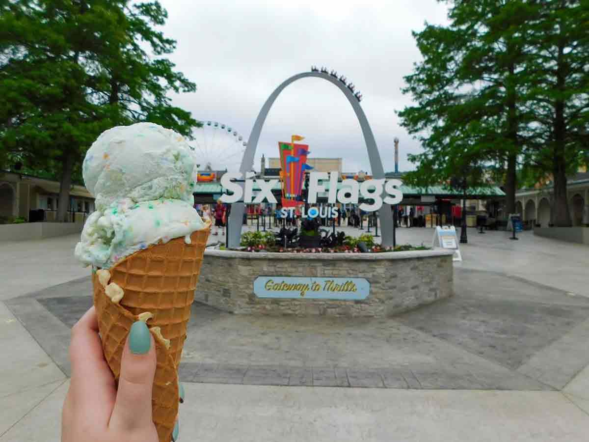 an ice cream cone held up in front of the six flags entrance sign