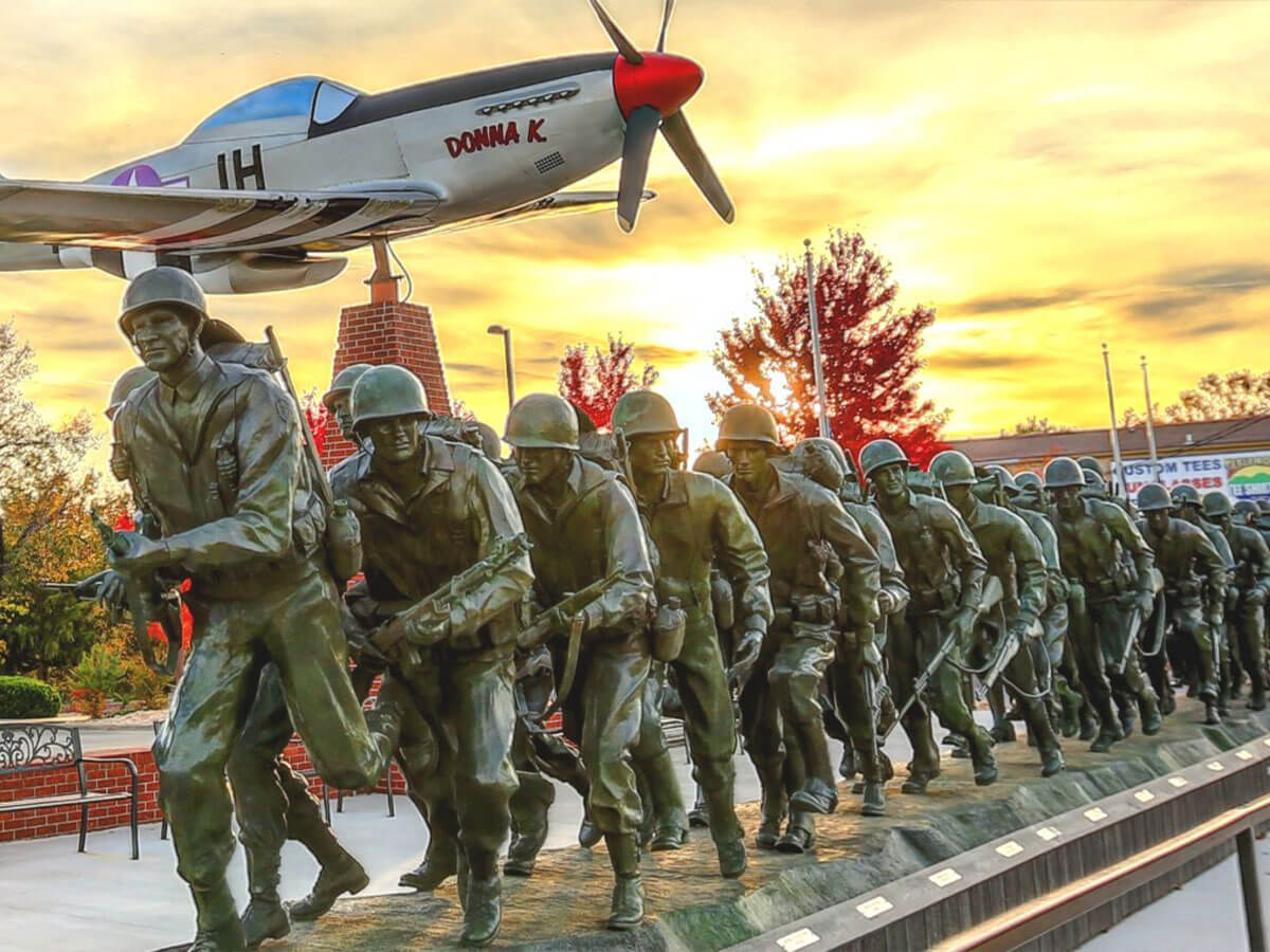 a large sculpture of a line of soldiers with a replica airplane in the background at the veterans memorial museum in branson