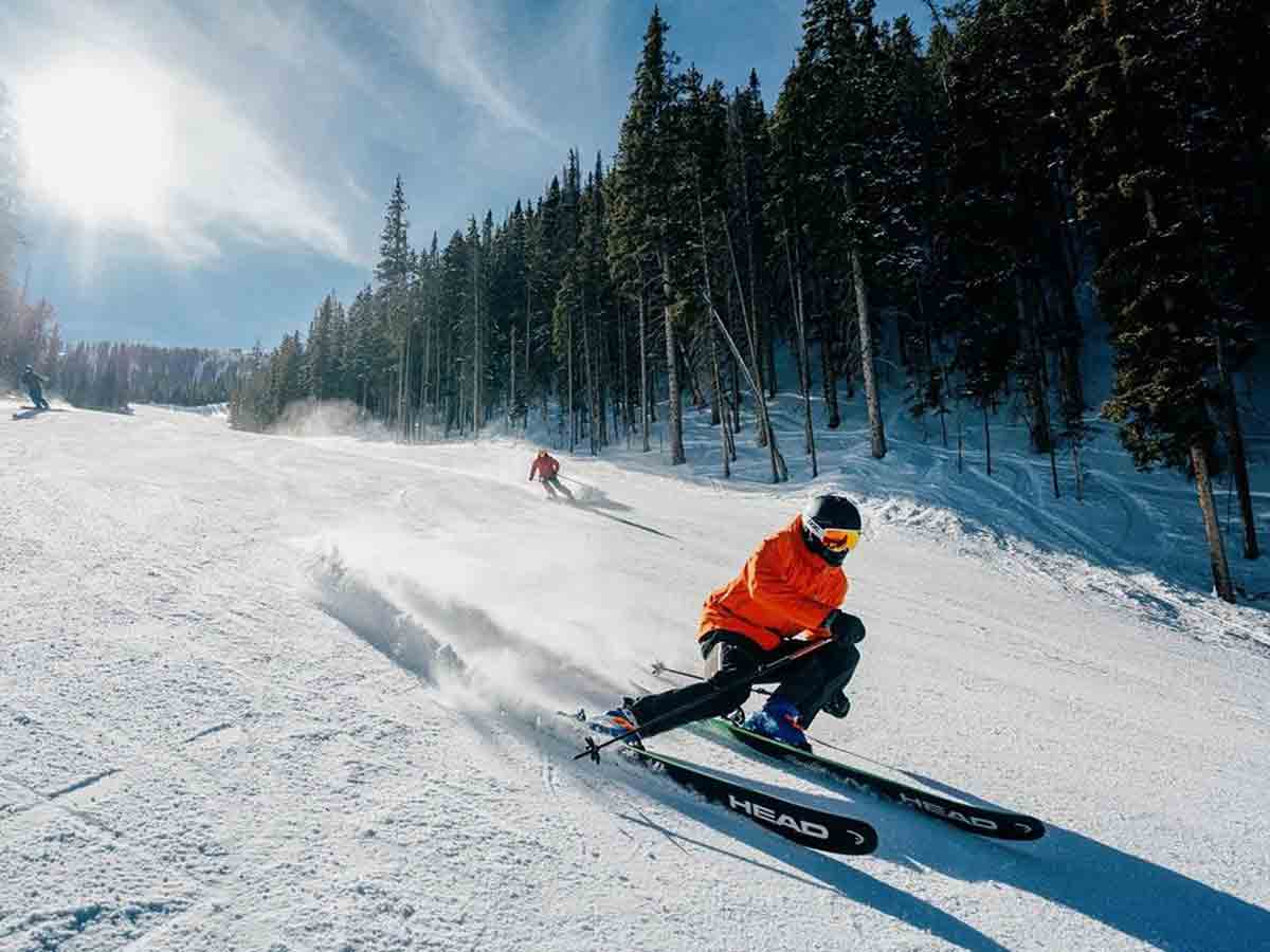 skiers make their way down snowy slopes in taos ski valley
