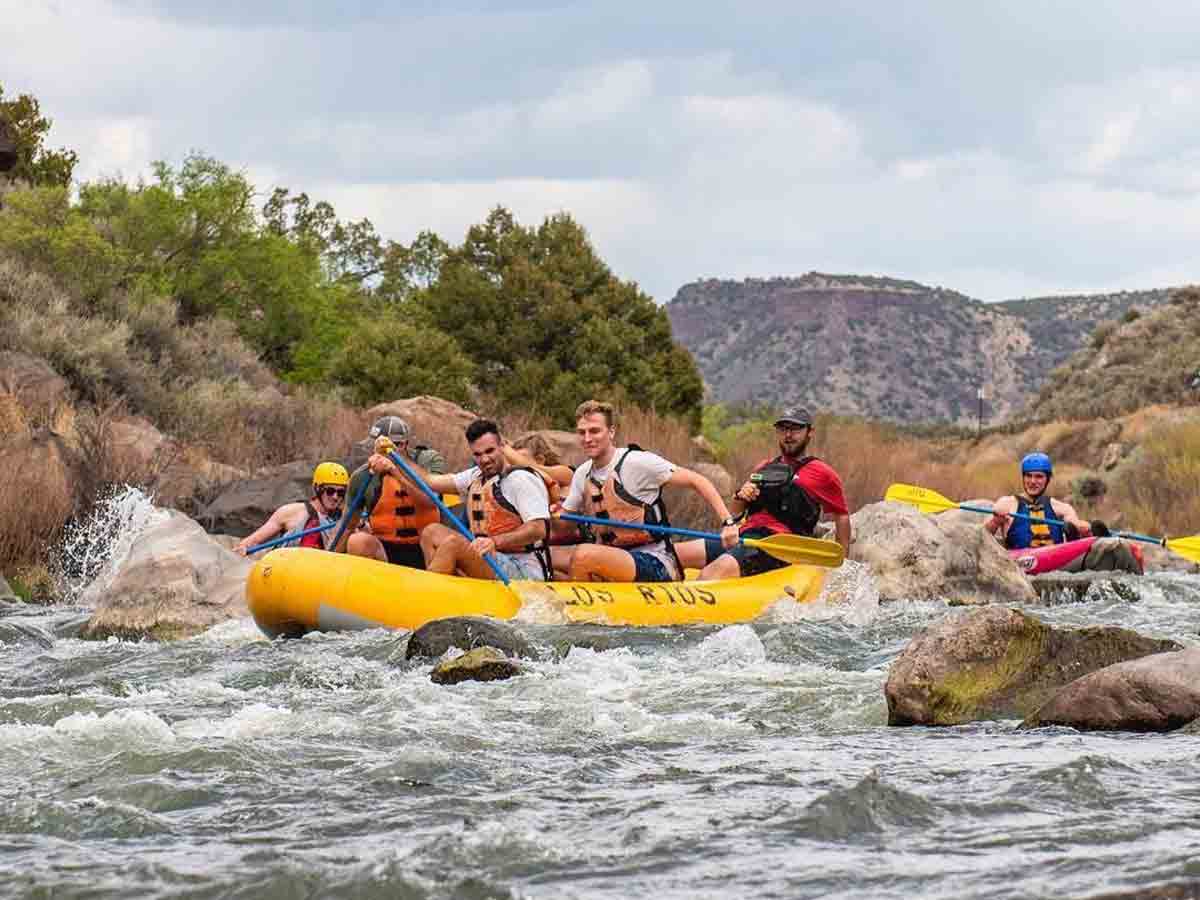 a group of white water rafters traverses rapids in an inflatable boat