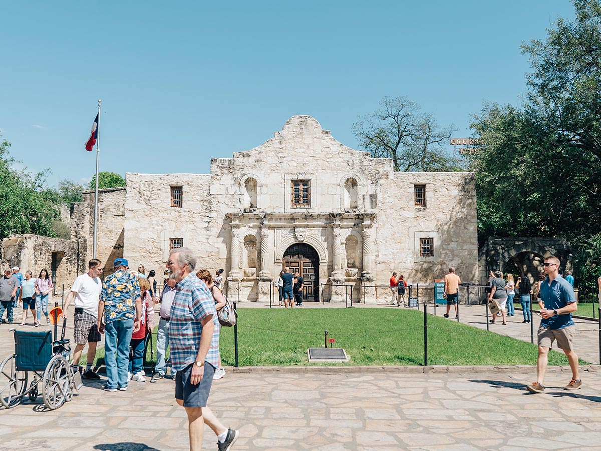 a view of visitors walking around the plaza in front of the alamo