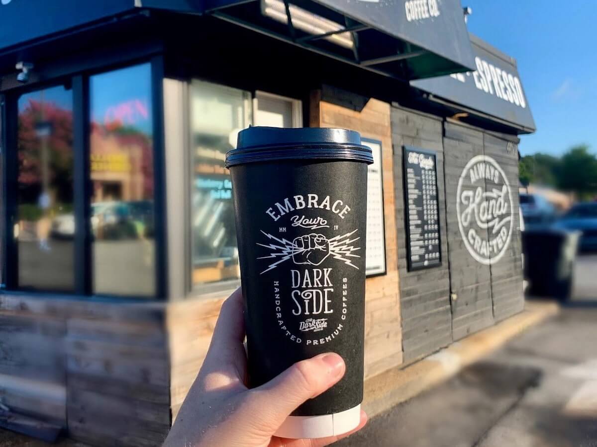 a cup of coffee held in front of the dark side coffee express stand in north little rock arkansas