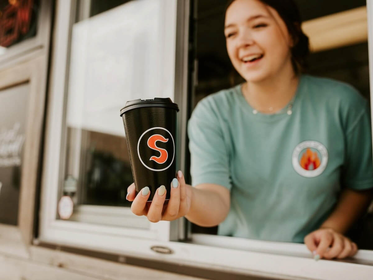 a barista hands coffee out the drive thru window to a customer at sadrachs in jonesboro