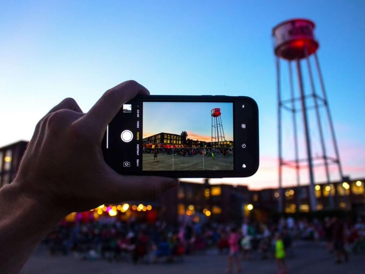 someone holds a phone up to take a picture of the water tower at the lowe mill arts & entertainment in huntsville alabama