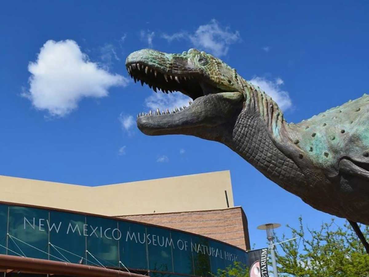 the exterior of the new mexico museum of natural history and a dinosaur sculpture outside the entrance