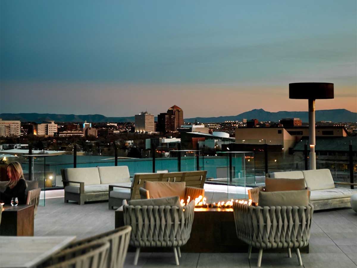 a rooftop restaurant patio at the hotel chaco overlooking the skyline of albuquerque new mexico
