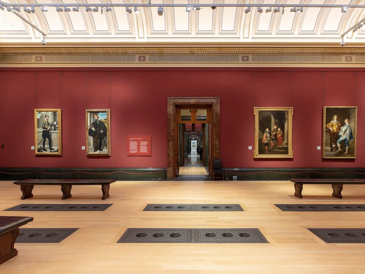 a view of one of the rooms of the national gallery with multiple paintings on a red wall
