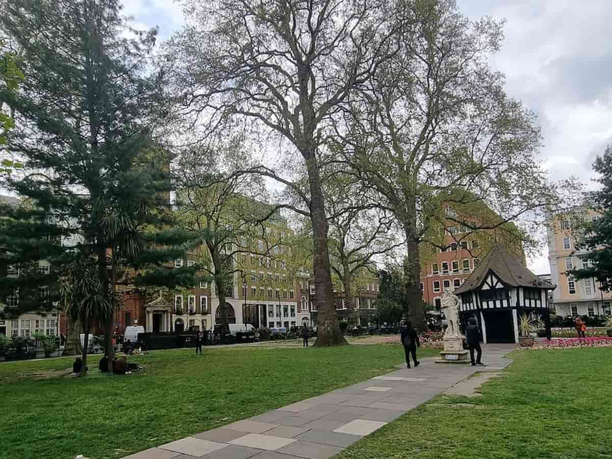 the green lawns of the soho square garden surrounded by city buildings