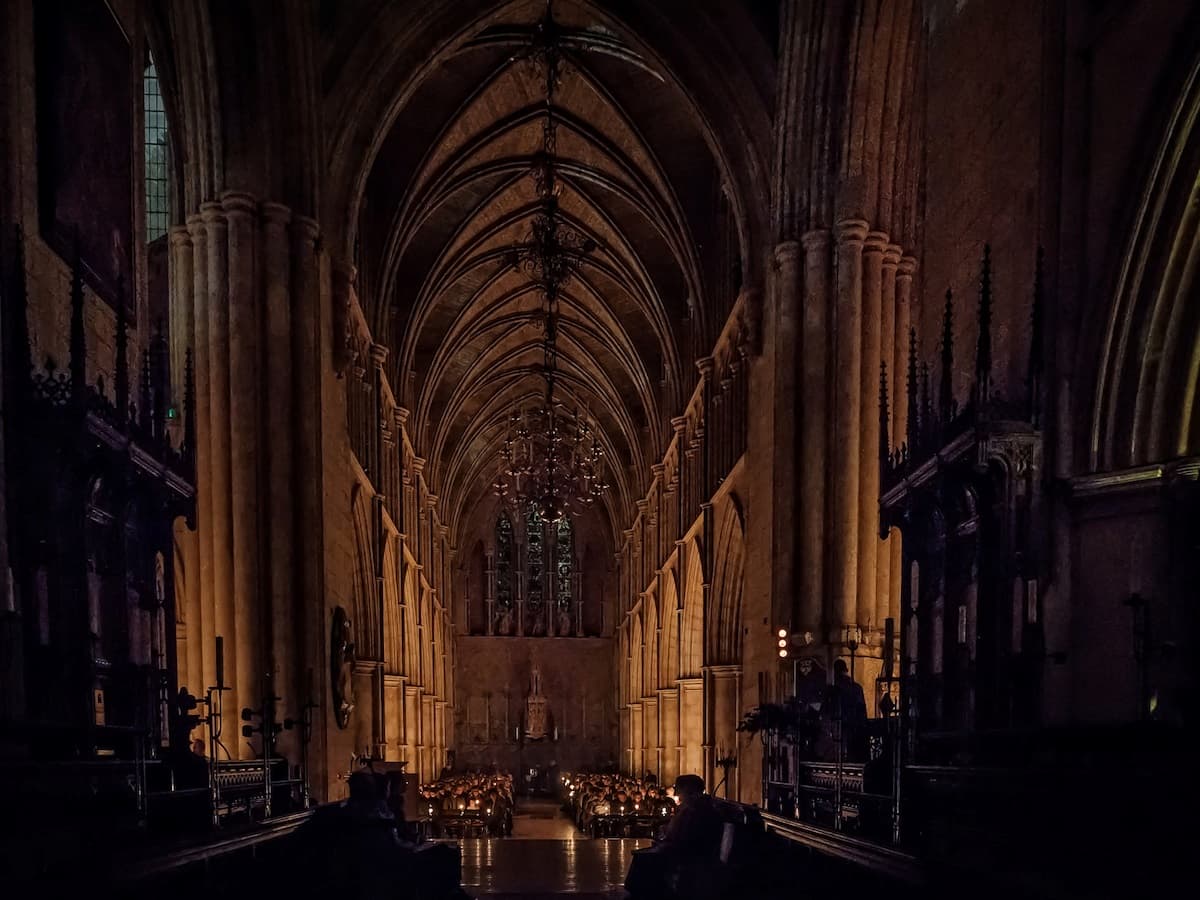 an interior view of southwark cathedral that is dimly lit with a choir holding candles
