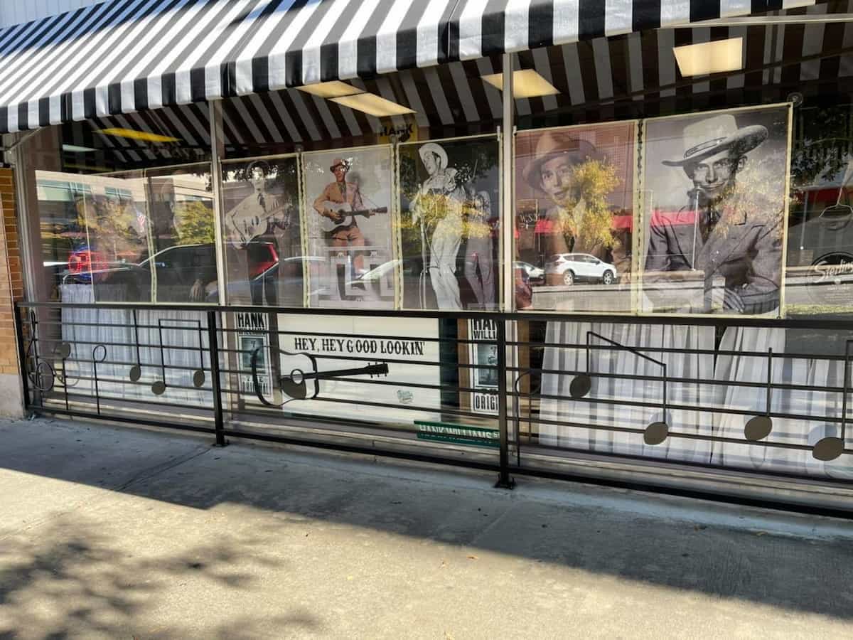 the exterior of the hank williams musuem with multiple hank williams posters displayed in the windows