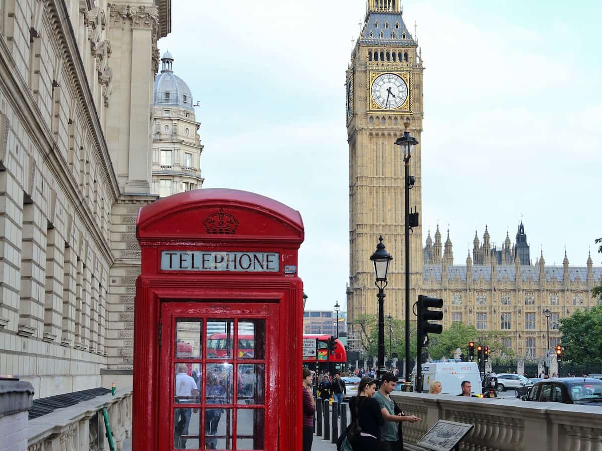 a traditional red phone box in front of big ben in london