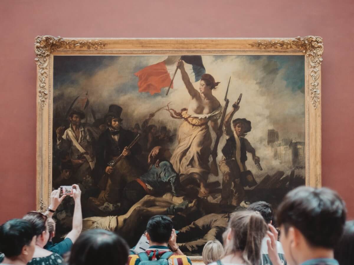 visitors crowd together to view a famous delacroix painting at the louvre