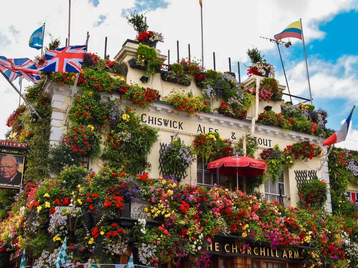 the colorful exterior of the churchill arms covered in plants and flowers in kensington london
