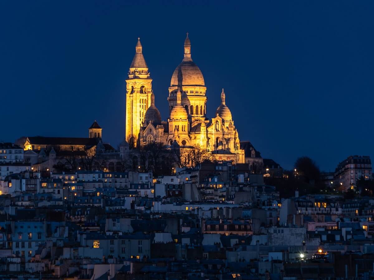 a view of sacré-cœur in paris lit up at night in lights on top of montmartre