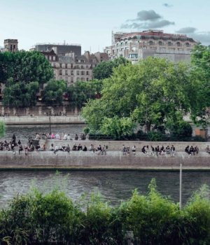 people sit along a wall alongside the seine river on the Île de la Cité in paris