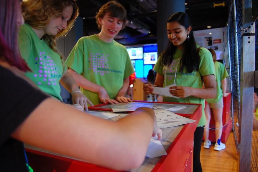 a group of kids working at a table in the museum of discovery in little rock