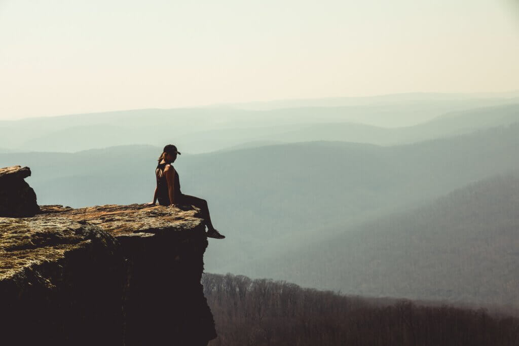 VIew of woman sitting on edge of rock formation at White Rock Mountain Recreation Area