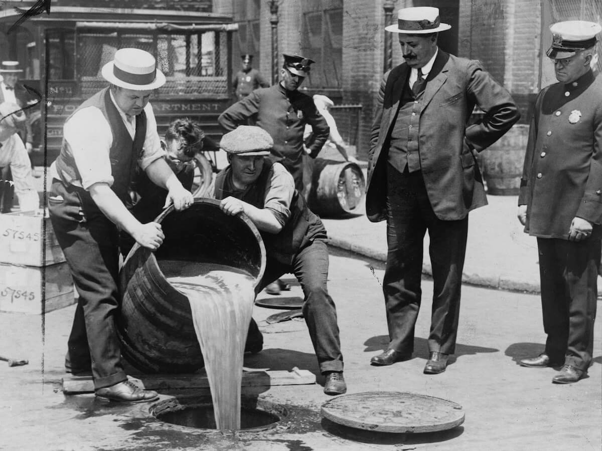 cops pour out alcohol in the street after a prohibition raid