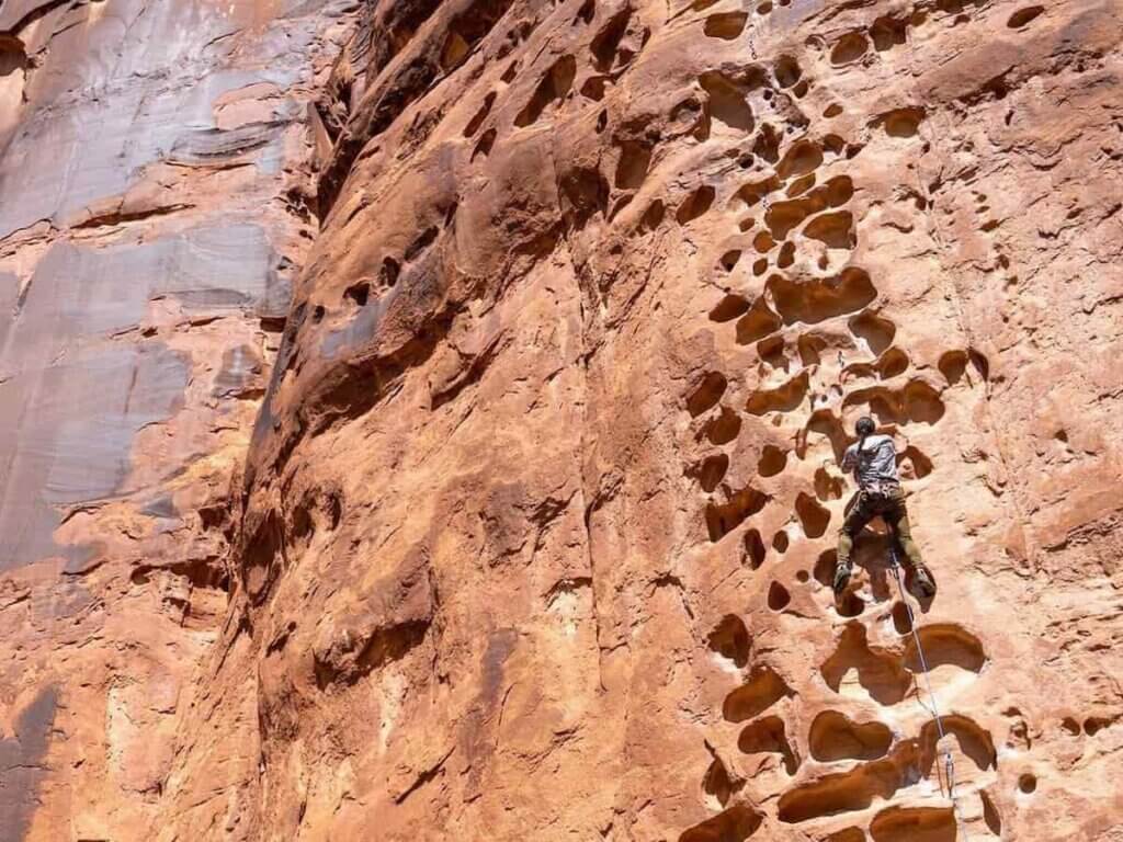 a person climbing a rock cliff near moab utah
