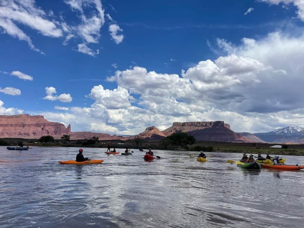 kayakers float down the colorado river in a large group near moab utah