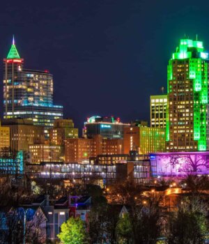 a nighttime view of the downtown raleigh, north carolina skyline with buildings lit up in neon lights of green and pink