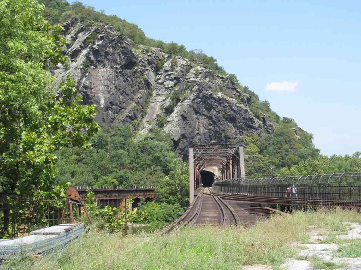 People walking across a historic railroad over a bridge at Harpers Ferry