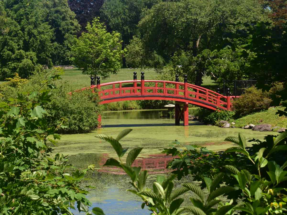 a red bridge over a pond at duke farms in new jersey
