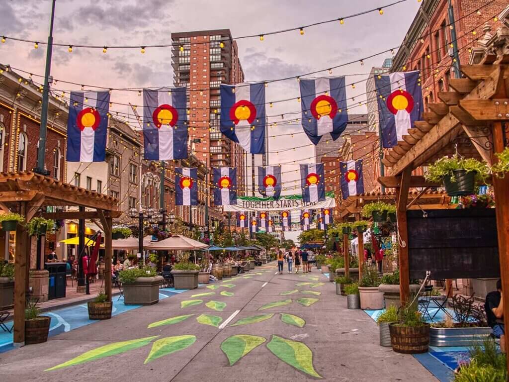 Street view with flags and lights hanging over the street in Denver, CO.