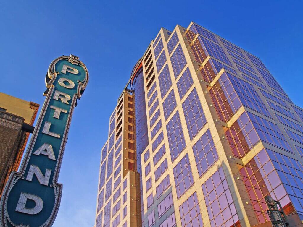 Skyward view of vertical "Portland" sign and skyscraper