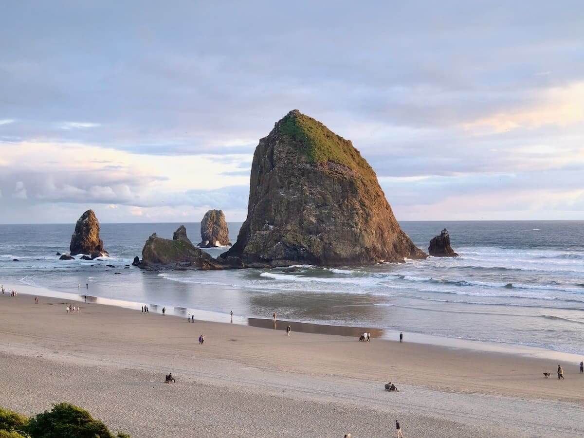 visitors take in the pretty scenery at cannon beach in oregon in the pacific northwest