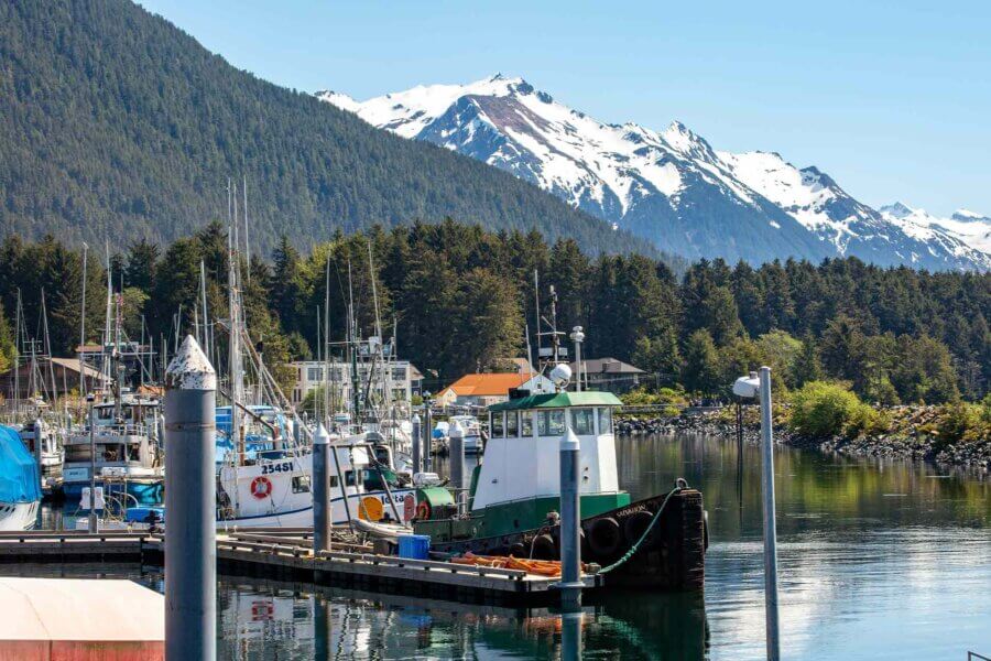 View of boats in water at Sitka, Alaska with snow-capped mountains in the background
