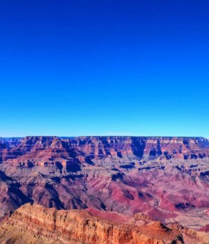 a blue sky over the red and orange terrain of the grand canyon in arizona
