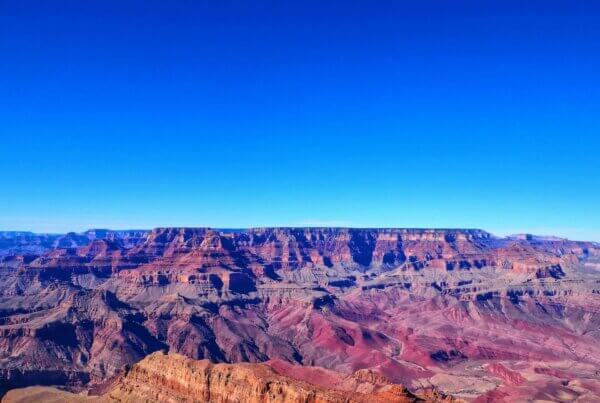 a blue sky over the red and orange terrain of the grand canyon in arizona