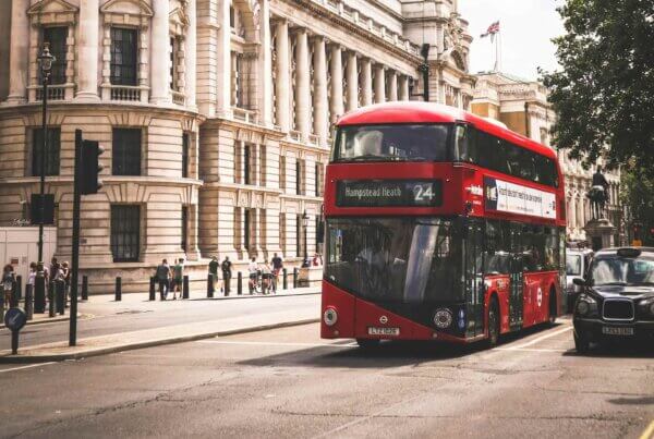 a famous red double decker london bus driving down the street