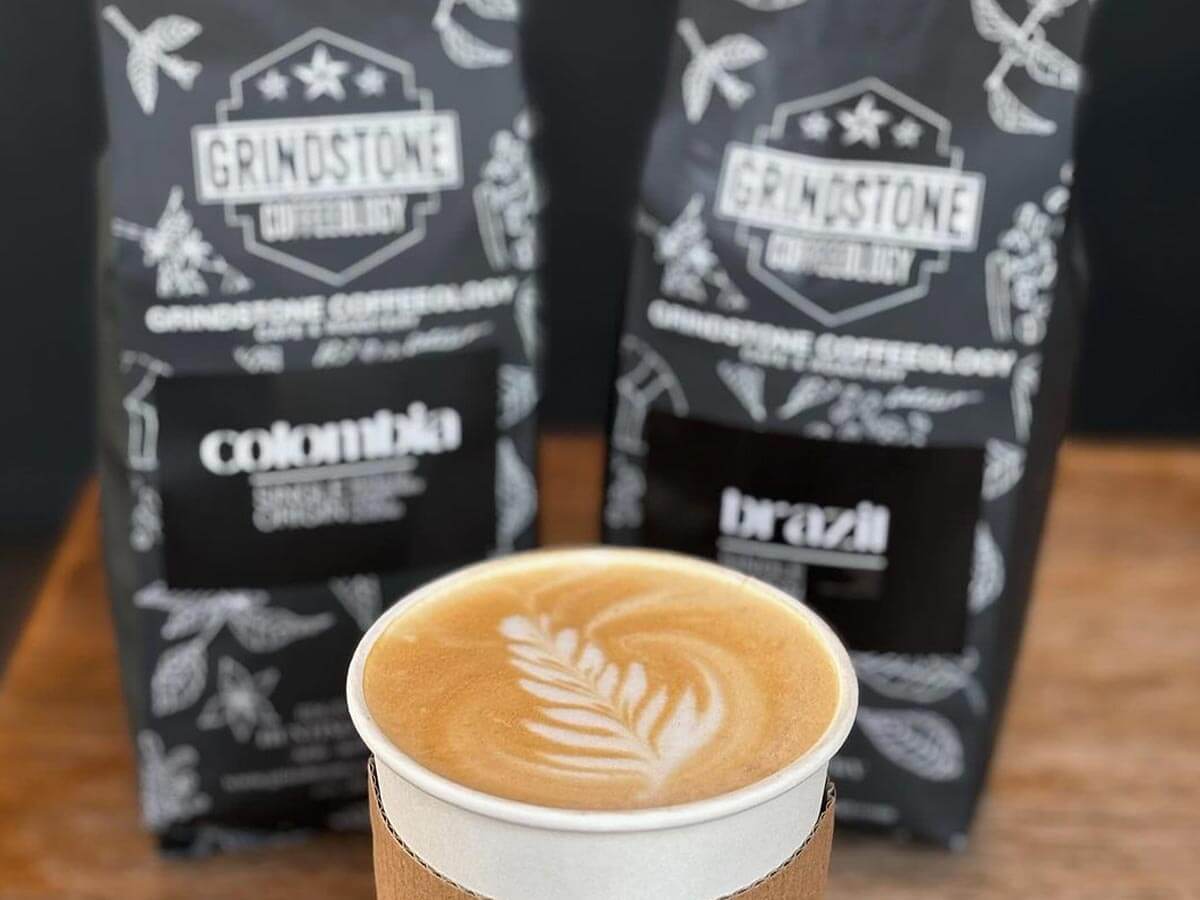 Grindstone Coffeeology bags of coffee grounds and cup of coffee