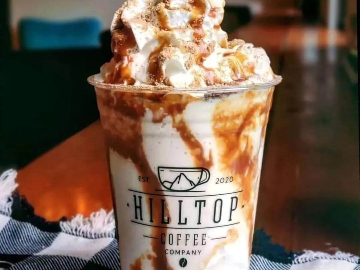 Hilltop Coffee Co cup of west virginia coffee with lots of whipped cream and caramel drizzle