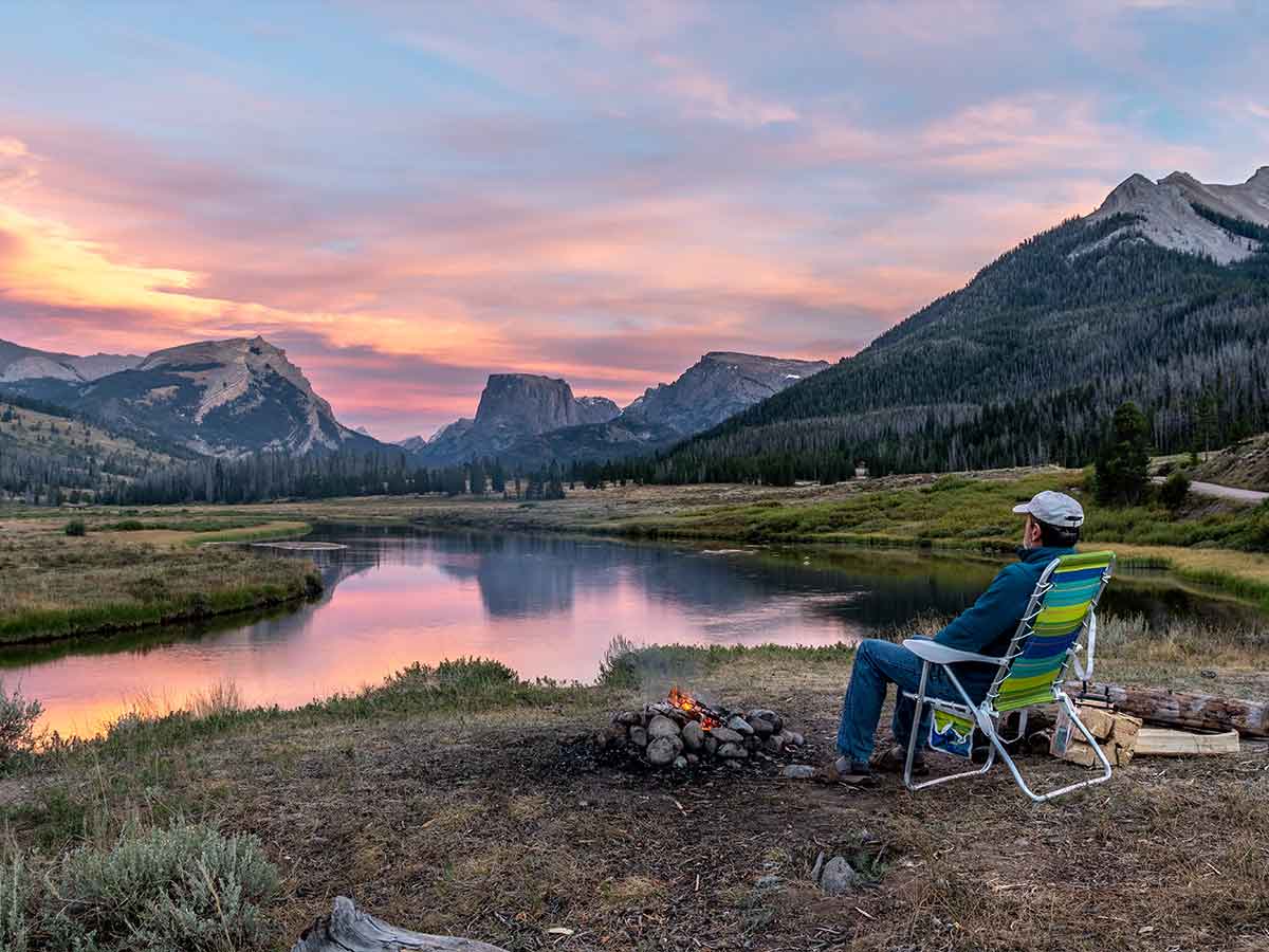 Person sitting in lawn chair admiring Wind River Range at dusk