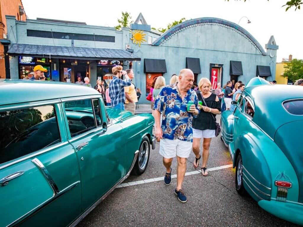 a couple strolls between antique cars in downtown covington, louisiana during a street party